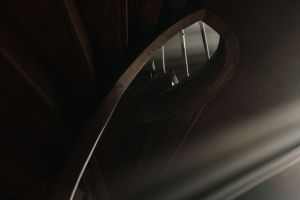 A beautifully crafted wooden spiral staircase with dramatic lighting creating an artistic curve effect.
