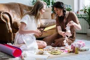 Two women enjoying a DIY crafting session indoors, surrounded by various crafting materials.