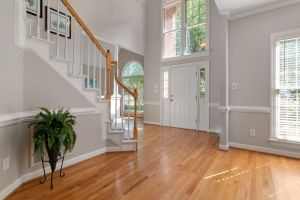 Elegant entrance with a wooden staircase and large windows, perfect for modern interiors.