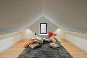 A serene attic room featuring colorful pillows and soft lighting, perfect for relaxation.