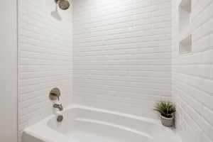 Bright minimalist bathroom with white subway tiles and a bathtub for a clean, contemporary feel.