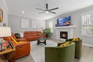 Bright living room featuring a leather sofa, fireplace, green armchairs, and a stylish rug for a cozy atmosphere.