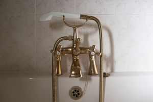 Close-up of a classic brass bathtub faucet with a ceramic hand shower in Greystoke, England.