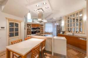 Interior of house with open kitchen with chairs and counter near cabinets next to door and window
