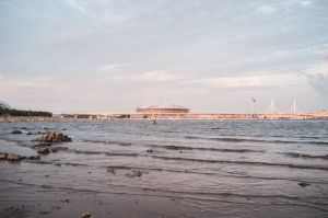 A beautiful view of Saint Petersburg's waterfront with a stadium and bridge at sunset.