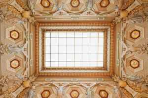 A beautifully designed ceiling with intricate details and a central skylight.