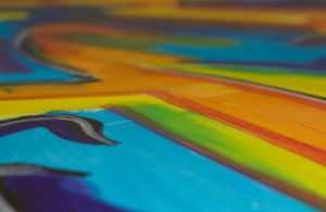 Close-up of a colorful abstract painting featuring bold, vibrant hues and dynamic brushstrokes.