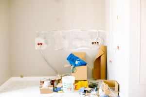 A room undergoing renovation with tools, supplies, wiring, and paint cans scattered around.