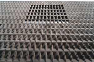 Concrete building facade with geometric patterns and recessed windows, showcasing modern architecture.