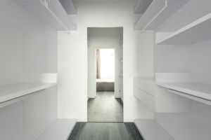 Bright and spacious modern minimalist walk-in closet with open shelving.