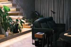 Stylish living room with greenery, stairs, and soft lighting. Cozy and modern decor.