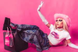 Fashionable model in Y2K style posing in a studio with vibrant pink background.