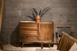 Elegant wooden cabinet against a stone wall, embodying rustic and minimalist decor in Hue, Vietnam.