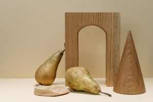 A minimalist still life composition featuring pears with geometric wooden shapes on a beige background.
