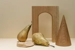 A minimalist still life composition featuring pears with geometric wooden shapes on a beige background.
