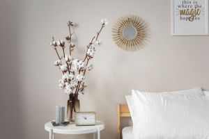 A calming bedroom scene with cotton flowers and modern decor details like a mirror and wall art.