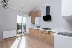 Stylish empty kitchen with wooden cabinets and large windows.