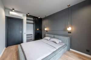 Contemporary minimalist style interior design of bedroom with comfortable bed placed near gray wall and with hanging and ceiling LED lamps