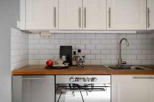 Stylish modern kitchen interior with white cabinets and wooden countertop, featuring kitchen essentials.