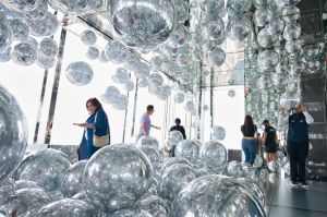 Visitors explore a reflective art installation with mirrored spheres at a New York City observation deck.