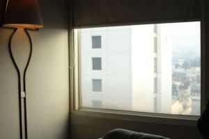 Cozy apartment interior with a glowing lamp, showcasing a city view through the window.