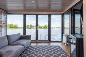 Spacious living room with floor-to-ceiling windows overlooking a serene lake.
